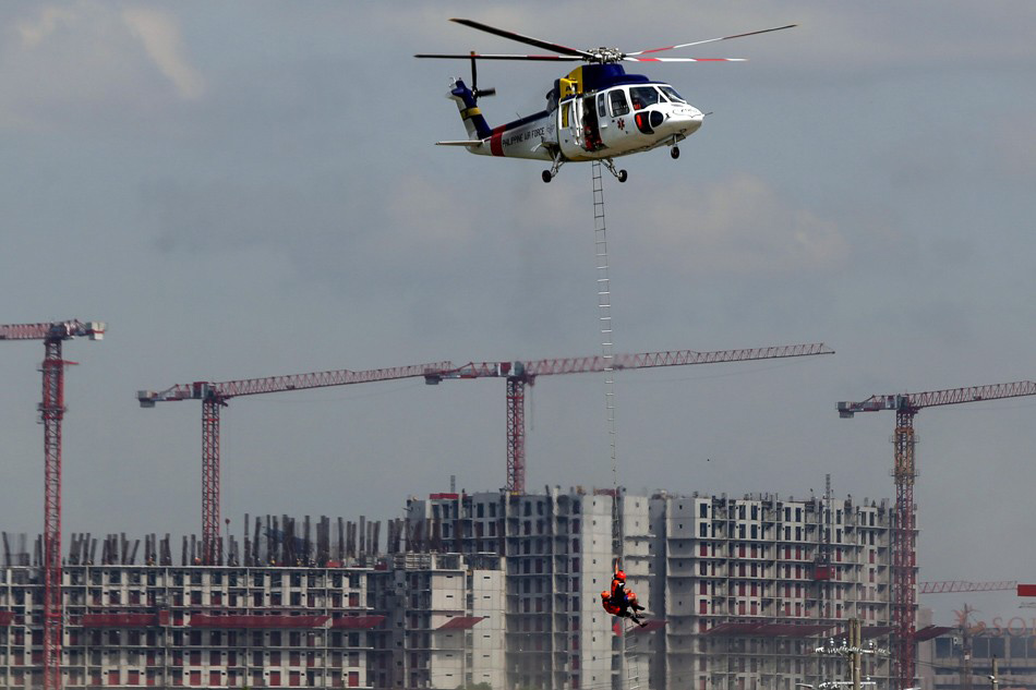 Rescuers hang from a ladder as a rescue helicopter hovers to a safer place in a tsunami scenario during the 4th Quarter Nationwide Simultaneous Earthquake Drill (NSED) in Paranaque City on Thursday. ABS-CBN News.