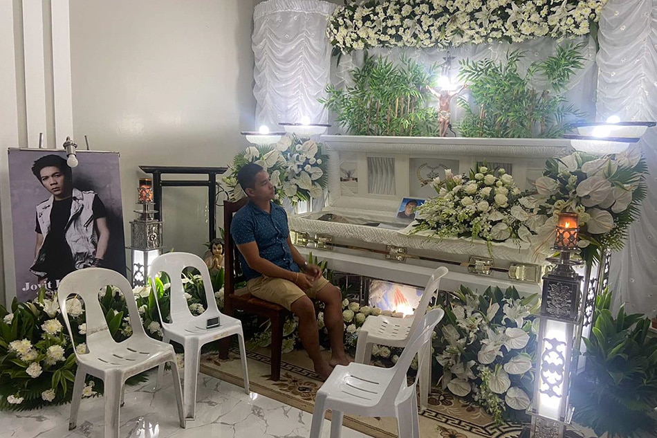 A cousin of Jovit Baldivino sits beside his casket at the family's home in Batangas City. Baldivino's wake will be open to the public for 1 day according to his family. ABS-CBN News