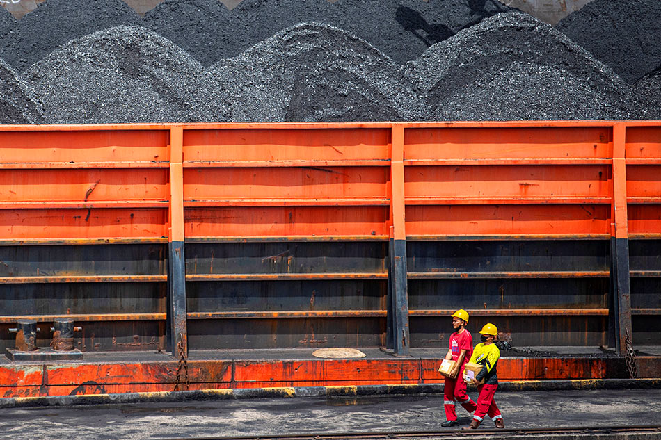 Workers walk near a tugboat carrying coal REUTERS