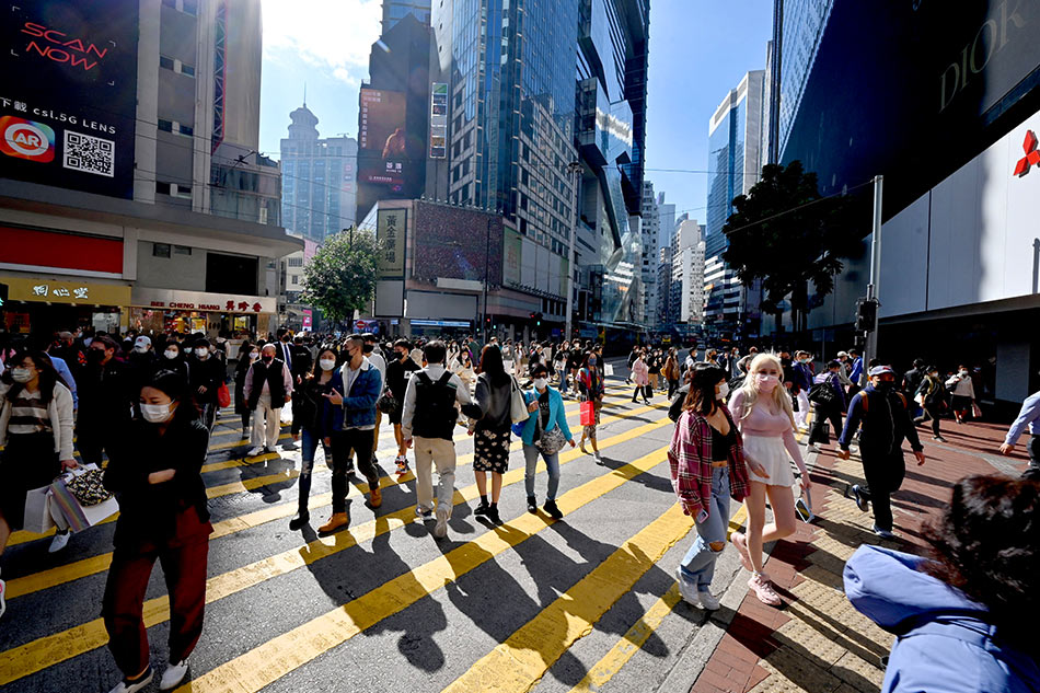 Pedestrians cross a busy intersection in Causeway Bay in Hong Kong on January 4, 2022. Peter Parks, AFP