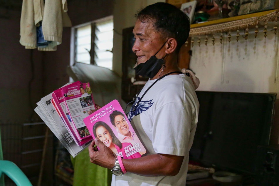 Carigo hold pamphlets and fans he and his daughter distribute. (George Calvelo, ABS-CBN News)