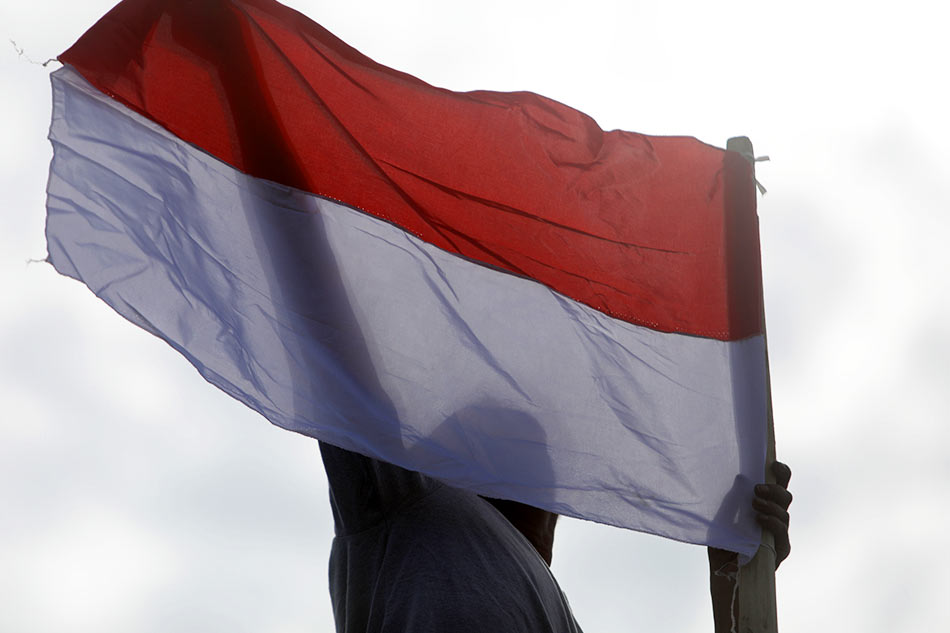  A man holds the Indonesian national flag EPA-EFE