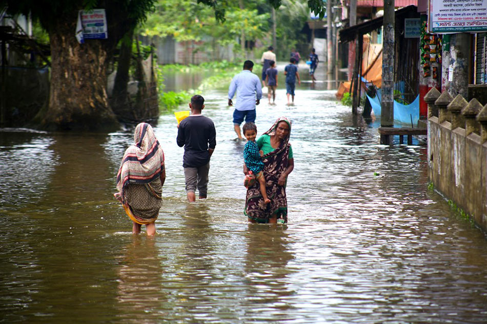 People wade through a flooded area AFP