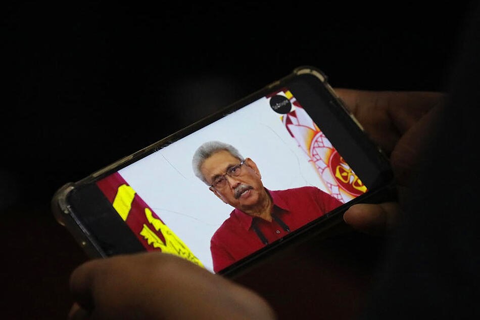 A person watches a video on a mobile phone of ousted Sri Lanka President Gotabaya Rajapaksa addressing the nation on television, in Colombo, Sri Lanka, on May 11, 2022. Chamila Karunarathne, EPA-EFE/File