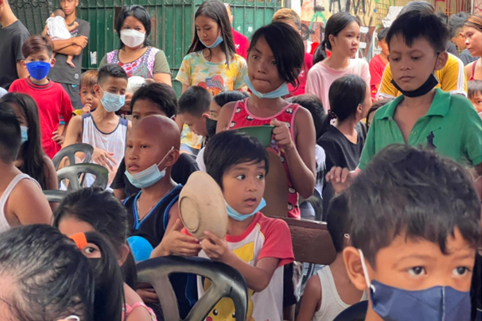 Children wait their turn to receive food and slippers. Handout