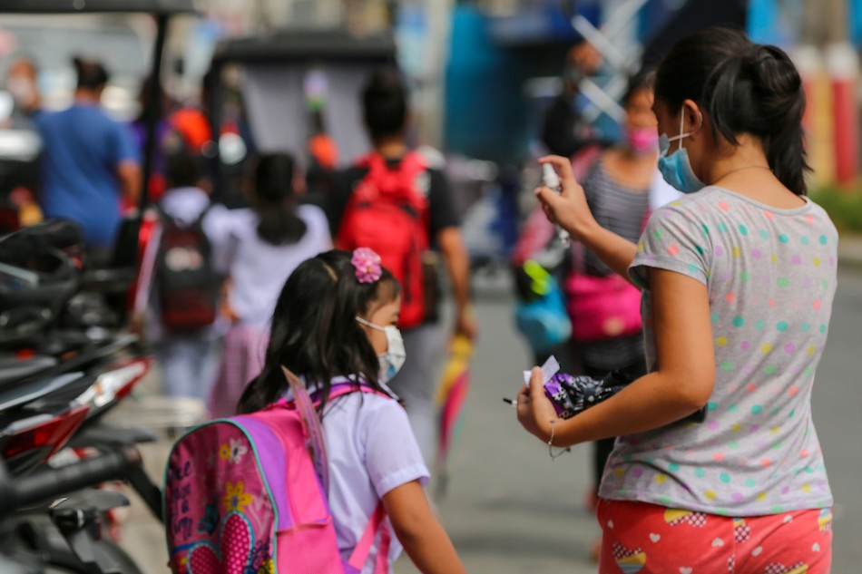 A mother sanitizes her child after attending the first day of face-to-face classes at the Ricardo P. Cruz Sr. Elementary School in Taguig City on Dec. 6, 2021. Jonathan Cellona, ABS-CBN News/File