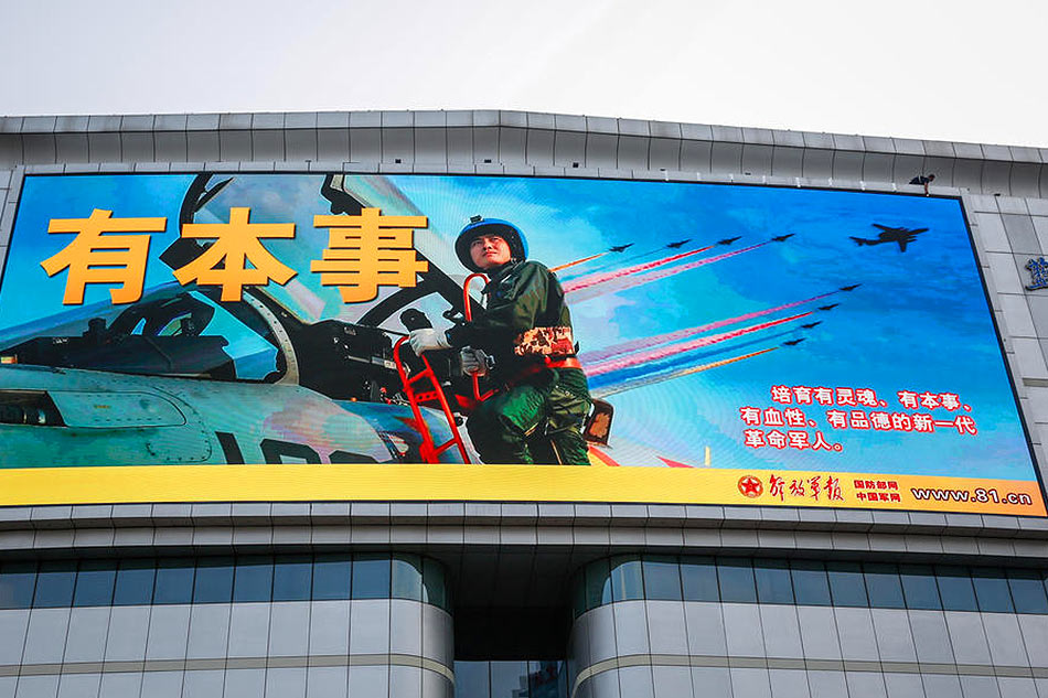 A man puts a tape along an advertisement to mark the 95th founding anniversary of the People's Liberation Army (PLA) displayed in Beijing, China on August 1, 2022. Mark R. Cristino, EPA-EFE/file