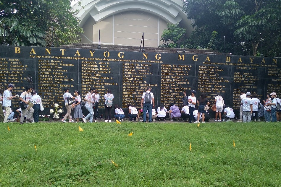 Participants of the rolling history bus tour offer flowers and candles at the Bantayog ng mga Bayani in Quezon City on Sept. 18, 2022, days before the 50th anniversary of the late President Ferdinand Marcos Sr.'s declaration of Martial Law in the country, which resulted in human rights violations and massive corruption. Nico Bagsic, ABS-CBN News