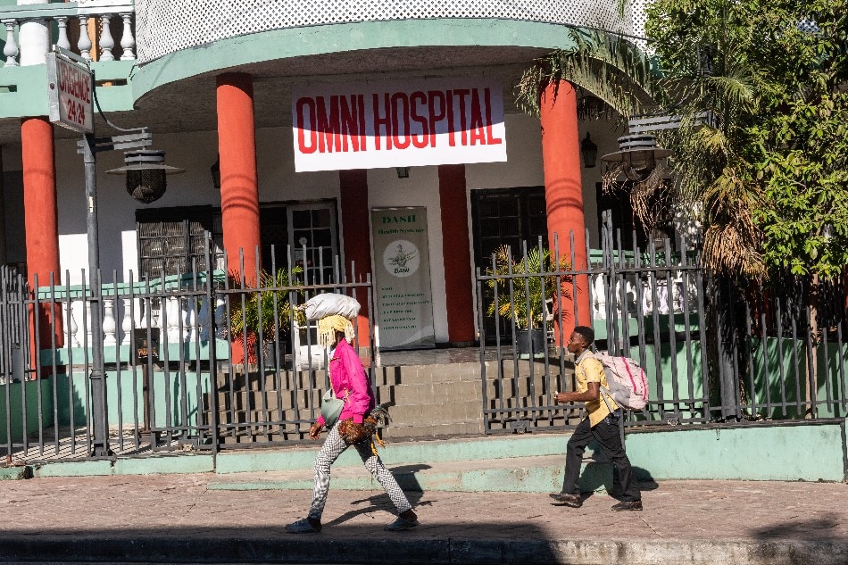 People walk in front of a hospital, in Port-au-Prince, Haiti on Sept. 30, 2022. After several days of protests in many cities in the country, activities are beginning to resume in the capital, although there is no public transport or gasoline at the stations. Johnson Sabin, EPA-EFE