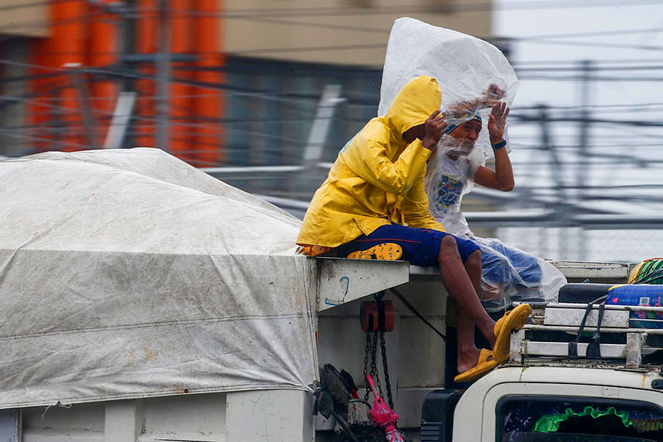 Workers protect themselves from rain while riding atop a garbage truck in Quezon City, on October 29, 2022. Rolex dela Pena, EPA-EFE