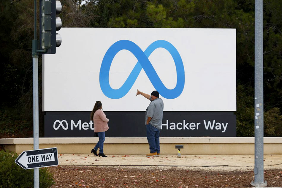 People stand in front of a Meta sign at the headquarters of Meta Platforms Inc., formerly named Facebook, Inc., in Menlo Park, California, USA, 08 November 2022. Chief Executive Mark Zuckerberg told company executives that Meta will begin laying off employees on 09 November. EPA-EFE/JOHN G. MABANGLO