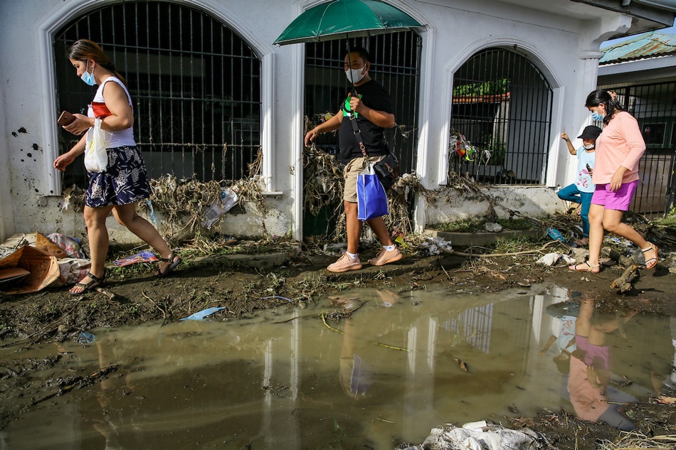 Residents clean and navigate through mud and debris brought by tropical storm Paeng as they visit departed loved ones at the Noveletea Municipal Cemetery in Cavite on November 1, 2022, All Saints Day. Jonathan Cellona, ABS-CBN News/File