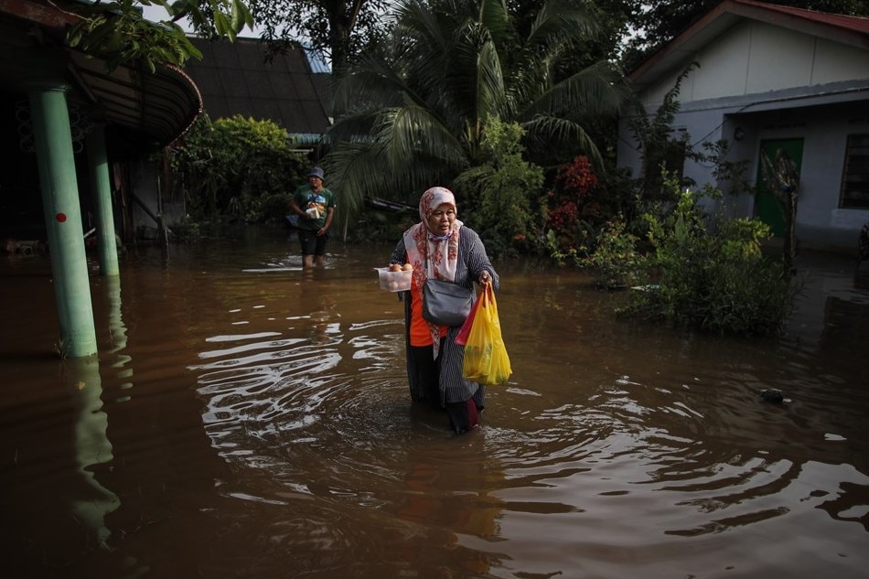 A woman holds eggs and food while walking through flood waters ahead of 15th General Election in Klang, state of Selangor, Malaysia, 12 November 2022. Some houses in several parts of the state of Selangor are still flooded after the flash flood occurred on 10 November. Fazry Ismail, EPA-EFE 