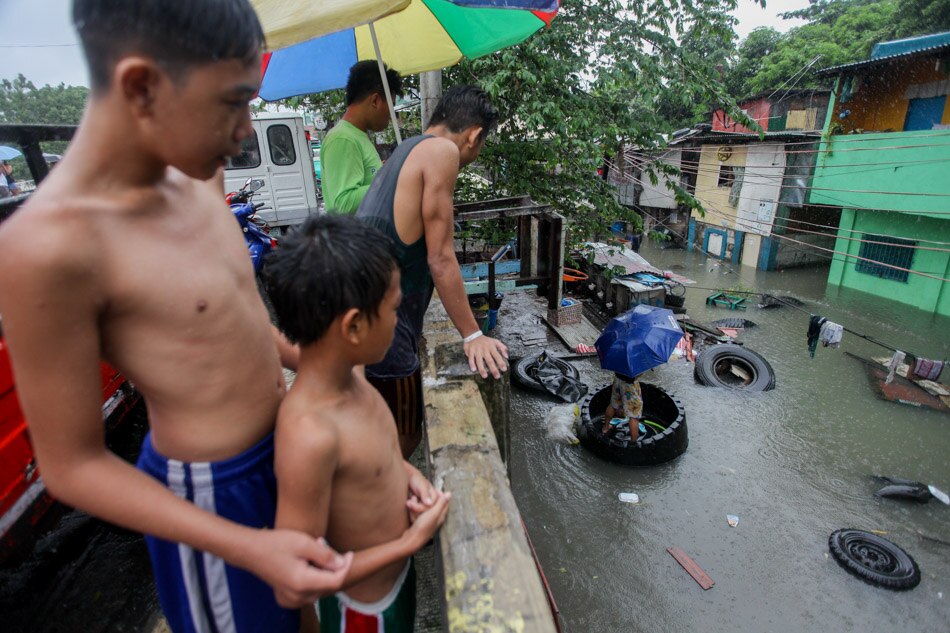 A resident uses a rubber tire to move across a flooded street near the creek in Roxas District, Quezon City after a heavy rainfall on July 17, 2018. Basilio H. Sepe, ABS-CBN News