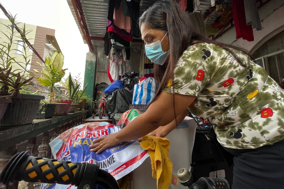 Cynthia Ludovice uses an election tarpaulin to prevent her belongings from getting wet as another threat of a heavy downpour in their community becomes imminent. Rafael Bosano, ABS-CBN News