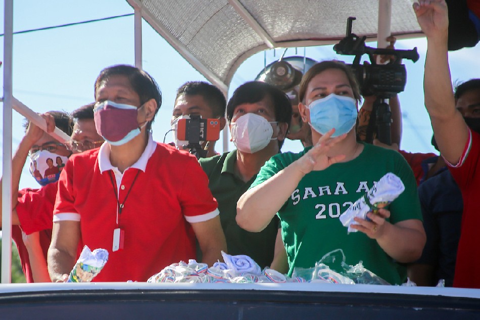 Presidential aspirant Ferdinand Marcos, Jr and running mate Davao City vice mayor Sara Duterte greet supporters during the team's grand caravan along Commonwealth Avenue in Quezon City on December 8,2021. Jonathan Cellona, ABS-CBN News/File