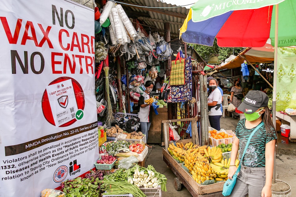 A sign requiring vaccine cards for entry is posted at the entrance of a public market in Taguig City on January 15, 2022. George Calvelo, ABS-CBN News
