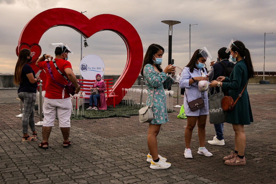 People take selfies with a heart installation backdrop at the SM by the Bay at the Mall of Asia in Pasay City on February 13, 2021. George Calvelo, ABS-CBN News