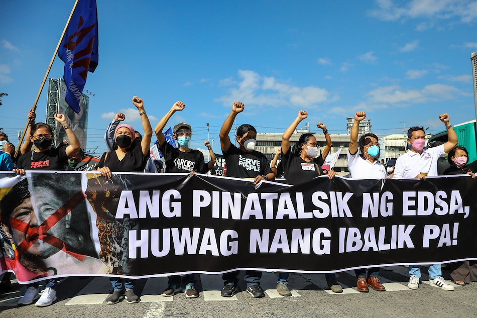 Protesters raise placards against the Marcos dictatorship as they join celebrations for the 36th anniversary of the EDSA People Power revolution at the People Power Monument on EDSA in Quezon City on February 25, 2022. Thirty-six years ago, thousands gathered outside the police and army camps on the same site to call for an end to the dictator Ferdinand Marcos Sr.'s 21-year rule. Jire Carreon, ABS-CBN News