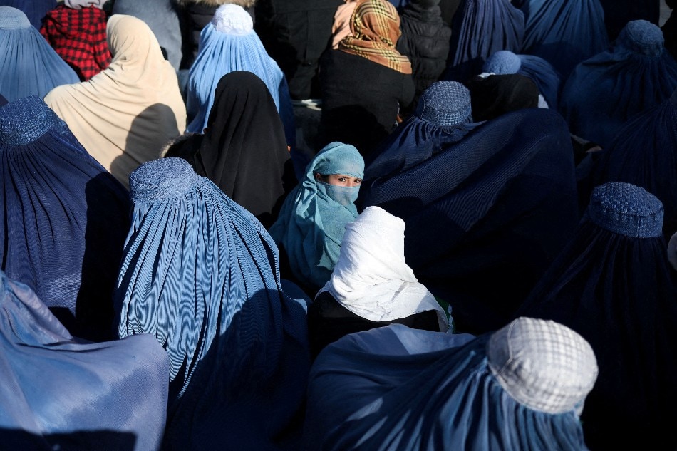 A girl sits in front of a bakery in the crowd with Afghan women waiting to receive bread in Kabul, Afghanistan, Jan. 31, 2022. Ali Khara, Reuters