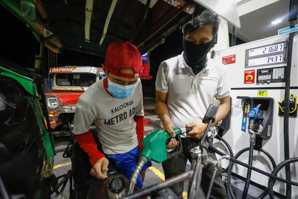 A gas station attendant (right) refuels a tricycle as its driver (left) looks on, in Quezon City. Rolex Dela Pena, EPA