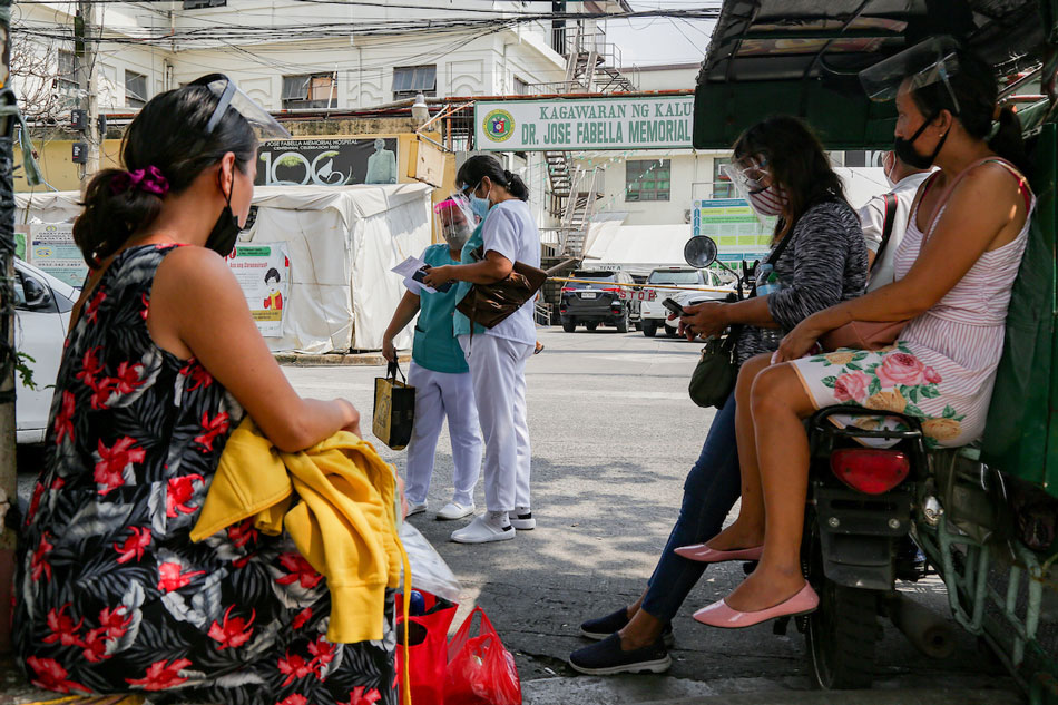 Health workers pass by as a pregnant woman and her companions wait for a ride home just outside the Dr. Jose Fabella Memorial Hospital in Manila on August 19, 2021. The hospital known for admitting pregnant women and their babies have seen an increase in COVID-19 cases. In a report, the hospital said that 30 mothers have mild COVID-19 and are showing no symptoms, while 3 newborns and 2 children also tested positive with the disease. George Calvelo, ABS-CBN News