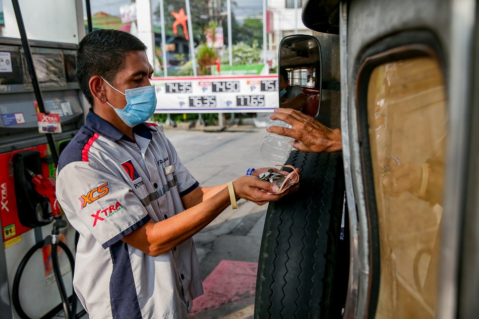 A gas station clerk receives a jeepney driver’s payment in coins at a station in Manila on March 15, 2022. George Calvelo, ABS-CBN News 