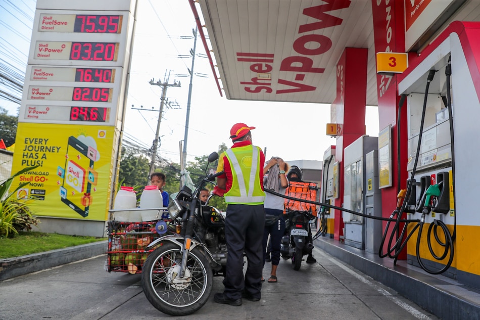 Buko vendor Rosel Borante pays for P50 worth of fuel at a nearby station after running out of gas and being forced to push her motorcycle along UN Avenue in Manila on March 15, 2022. Jonathan Cellona, ABS-CBN News