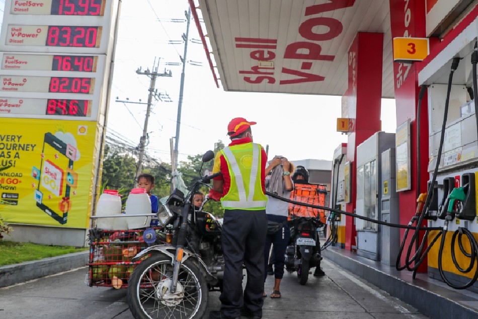 Buko vendor Rosel Borante pays for P50 worth of fuel at a nearby station after running out of gas and being forced to push her motorcycle along UN Avenue in Manila on March 15, 2022. Jonathan Cellona, ABS-CBN News/File