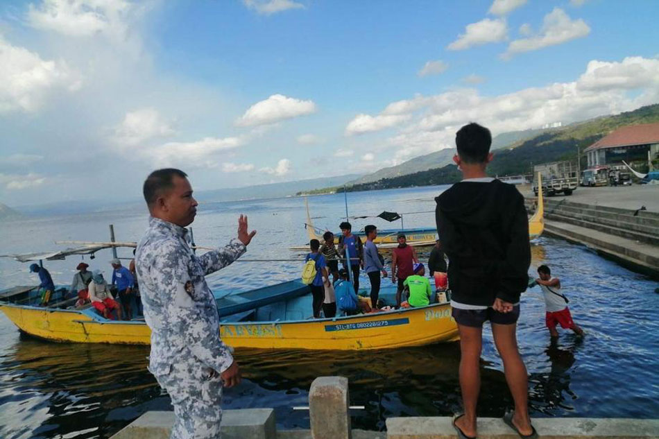 A handout photo made available by the Philippine Coast Guard (PCG) shows a coastguard personnel inspecting a fishing boat near the Taal volcano island in Batangas province, March 26, 2022. Villagers living near the volcano were evacuated after the Philippine Institute of Volcanology and Seismology (Phivolcs) placed Taal Volcano under Alert Level 3 after a series of short phreatomagmatic bursts. PCG/Handout/EPA-EFE 