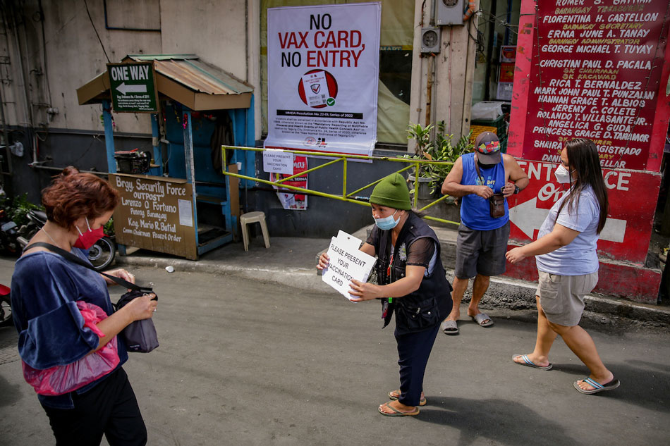 Barangay volunteers inspect vaccination cards of pedestrians and motorists passing through a busy road in Taguig City on January 21, 2022. The City of Taguig set up an “Enhanced Vaccination Checkpoint” as they strengthen their operations in line with the restriction of movement of unvaccinated individuals by the national government. George Calvelo, ABS-CBN News