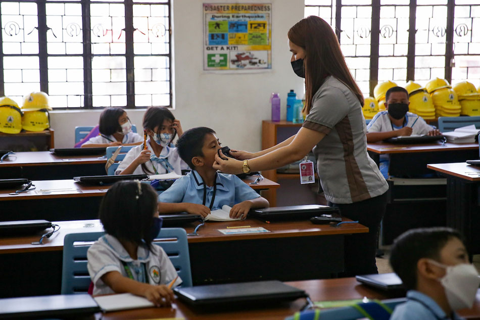 A teacher assists a student in wearing a facemask at the Jose Magsaysay Elementary School (JMES) in Makati City on March 30, 2022. George Calvelo, ABS-CBN News