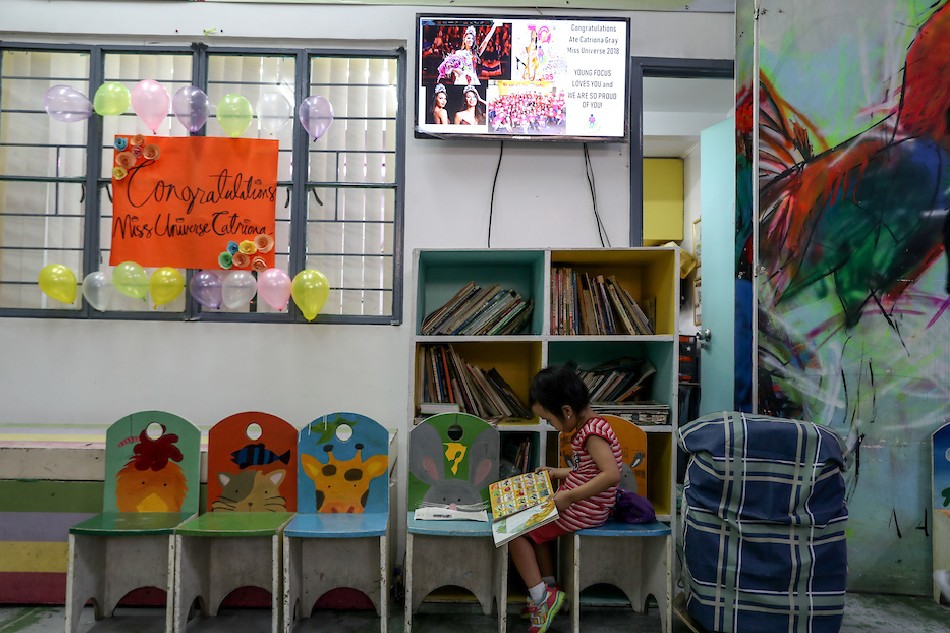 A young pupil reads her book beside the library at the Young Focus Foundation Child Care Center in Balut, Tondo, Manila. December 18, 2018. Jonathan Cellona, ABS-CBN News