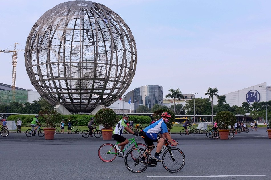 Bike riders pass by the globe near the facade of the Mall of Asia in Pasay City on September 26, 2020. George Calvelo, ABS-CBN News/File