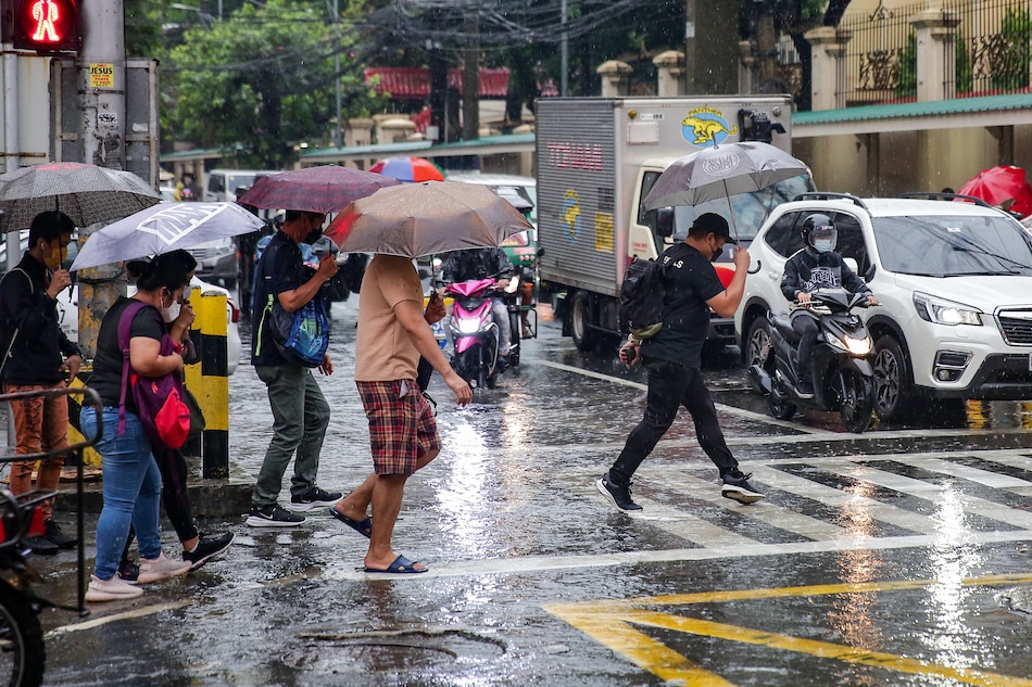 Pedestrians walk in the rain at an intersection in Manila on April 5, 2022. George Calvelo, ABS-CBN News/file