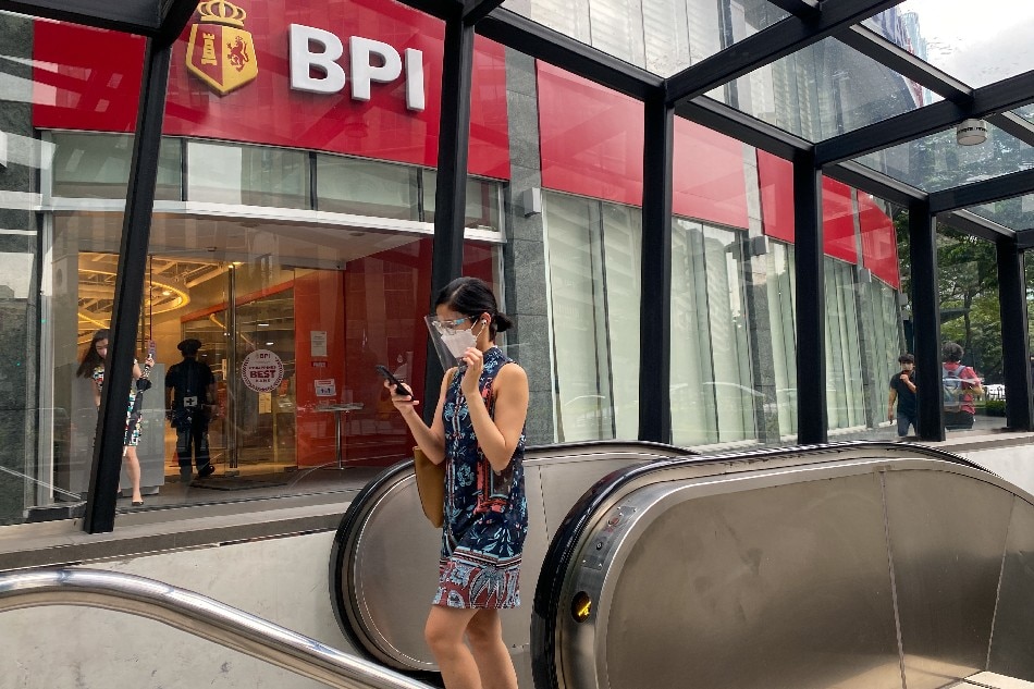 A passerby uses her mobile phone in front of a BPI branch in Makati City on Jan. 19, 2021. Jonathan Cellona, ABS-CBN News/File