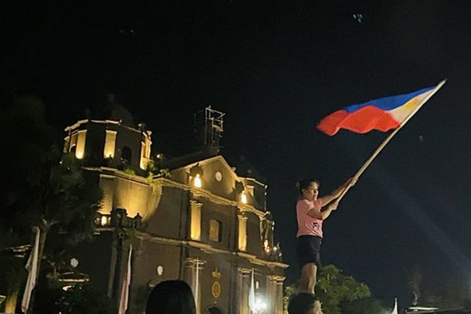 A woman waves the Philippine flag atop a vehicle in front of the Naga Metropolitan Cathedral after Archbishop Rolando Tirona holds the 'Misa ng Pagkakaisa at Pasasalamat,' attended by Vice President Leni Robredo with her family and close friends. Wena Cos, ABS-CBN News