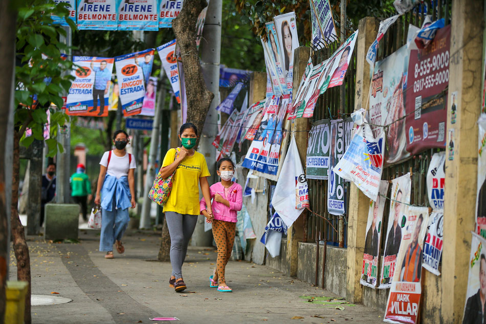 People pass by various campaign posters along C. P. Garcia in Quezon City on April 27, 2022. Jonathan Cellona, ABS-CBN News