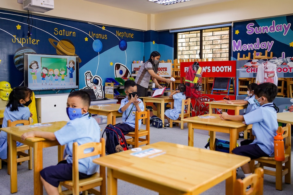 A teacher checks the temperature of students before starting their classes at the Jose Magsaysay Elementary School in Makati City on March 30, 2022. George Calvelo, ABS-CBN News