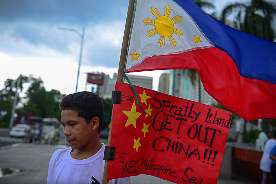  A boy holds a Philippine flag with a replica of Chinese flag below stating a call for China’s exit out of the West Philippine Sea during a protest in July 2016. Filipinos celebrated the verdict issued by the Permanent Court of Arbitration at The Hague regarding the country’s claim for maritime entitlement in the disputed features in the South China Sea. Nikon Celis, ABS-CBN News/FILE