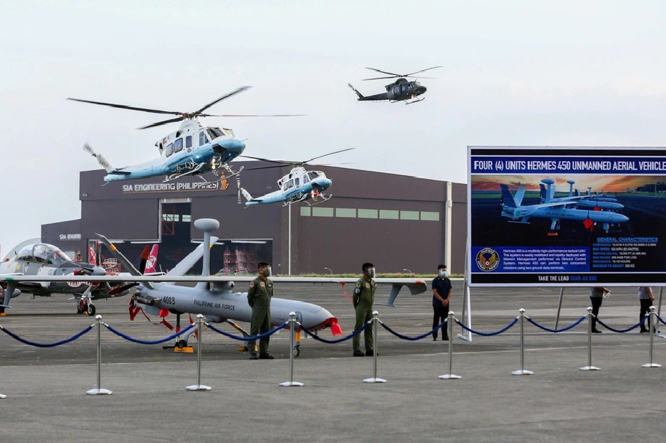 Helicopters including one carrying President Rodrigo Duterte are seen behind newly delivered air assets of the Philippine Air Force at the Haribon Hangar in Clark Air Base, Pampanga on Friday, February 12, 2021. The air assets include one C-130H cargo plane, six S70i Blackhawk utility helicopters, six A-29B Super Tucanos, six Hermes 900 Unmanned Aerial Vehicles and 4 Hermes 450 Unmanned Aerial Vehicles.
