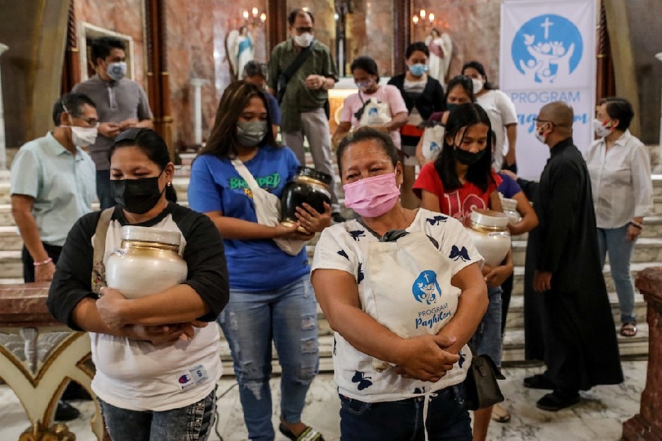 Family members and relatives receive the urns holding the ashes of victims of the war on drugs after a memorial service inside a Catholic church in Manila on November 15, 2021. Basilio H. Sepe, ABS-CBN News
