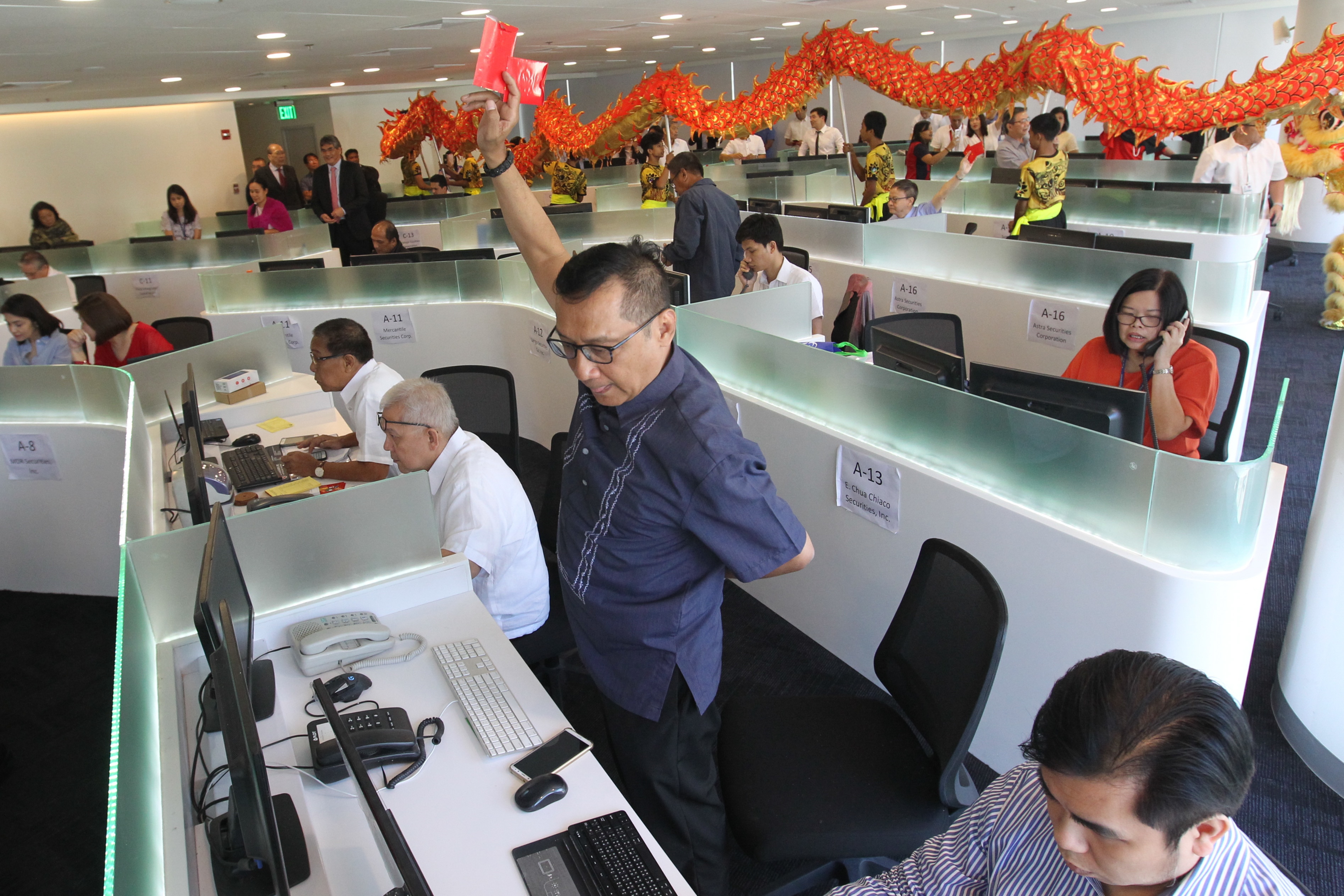 Traders work on their desks as lion dance performers approach their stations at the new Philippine Stock Exchange (PSE) headquarters at the Bonifacio Global City in Taguig on Monday, Feb. 19, 2018. George Calvelo, ABS CBN News/File