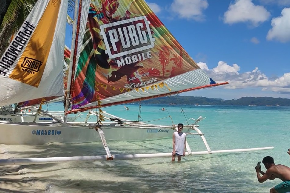 A fan poses for a photo with a game-inspired sailboat in Boracay on June 17, 2022 . Kennedy Caacbay, ABS-CBN News