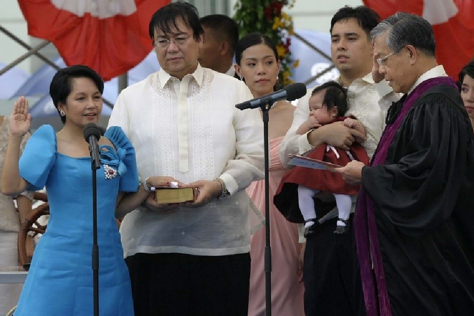 Gloria Macapagal-Arroyo (L) takes her oath of office as the 14th Philippine president during inauguration rites in Cebu. Photo by Rolex Dela Pena, EPA