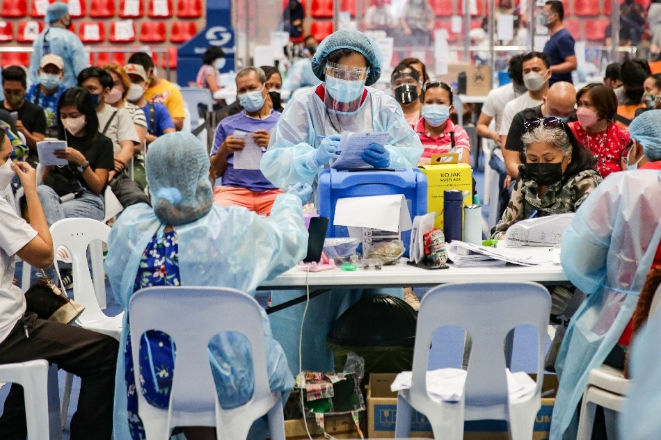 A health worker prepares to inoculate a woman for COVID-19 at a vaccination site inside the Makati Coliseum on January 15, 2022. George Calvelo, ABS-CBN News/file