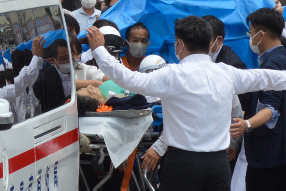 Former Japanese prime minister Shinzo Abe (C) is transported into an ambulance near Yamato Saidaiji Station after being shot in the city of Nara on July 8, 2022. Shinzo Abe was shot at a campaign event, a government spokesman said, as local media reported the nation's longest-serving premier was showing no vital signs. Yomiuri Shimbun/AFP