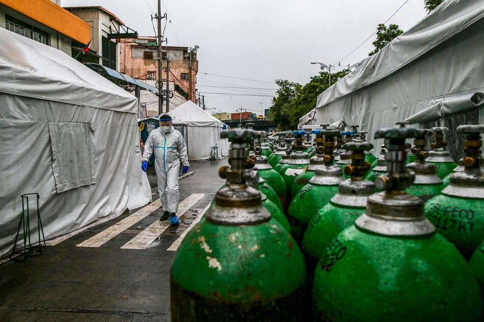 A health worker walks past tents and rows of oxygen tanks at Gat Andres hospital in Tondo, Manila, July 29, 2020 as the overall utilization of hospital beds dedicated for coronavirus disease (COVID-19) patients reached a critical level. Czar Dancel, ABS-CBN News