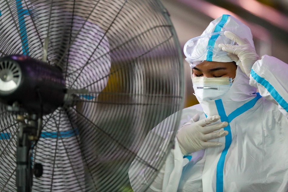 A  health worker in a PPE cools herself in front of an industrial fan at a testing center on August 20, 2020 as Navotas City required testing for residents and isolation if they tested positive. George Calvelo, ABS-CBN News