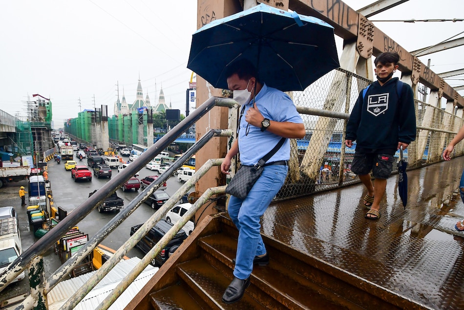 Pedestrians cross a footbridge as a traffic builds up along Commonwealth Avenue in Quezon City amid cloudy skies and light rain showers on August 8, 2022. Mark Demayo, ABS-CBN News